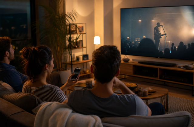 Tres personas miran un concierto en una televisión conectada mientras una usa un teléfono como segunda pantalla